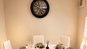 A round dining table with white chairs, set for a meal with plates, glasses, and a centerpiece. - Stylish 2-Bed Bedford Home | Sleeps 4 + Sofa Bed | Free Parking |Super Fast WiFi (Bedford)