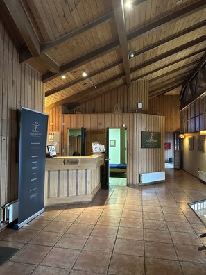 A reception area with a wooden reception desk, a sign for 'Casa Freude Hotel Boutique', and a reception counter.
