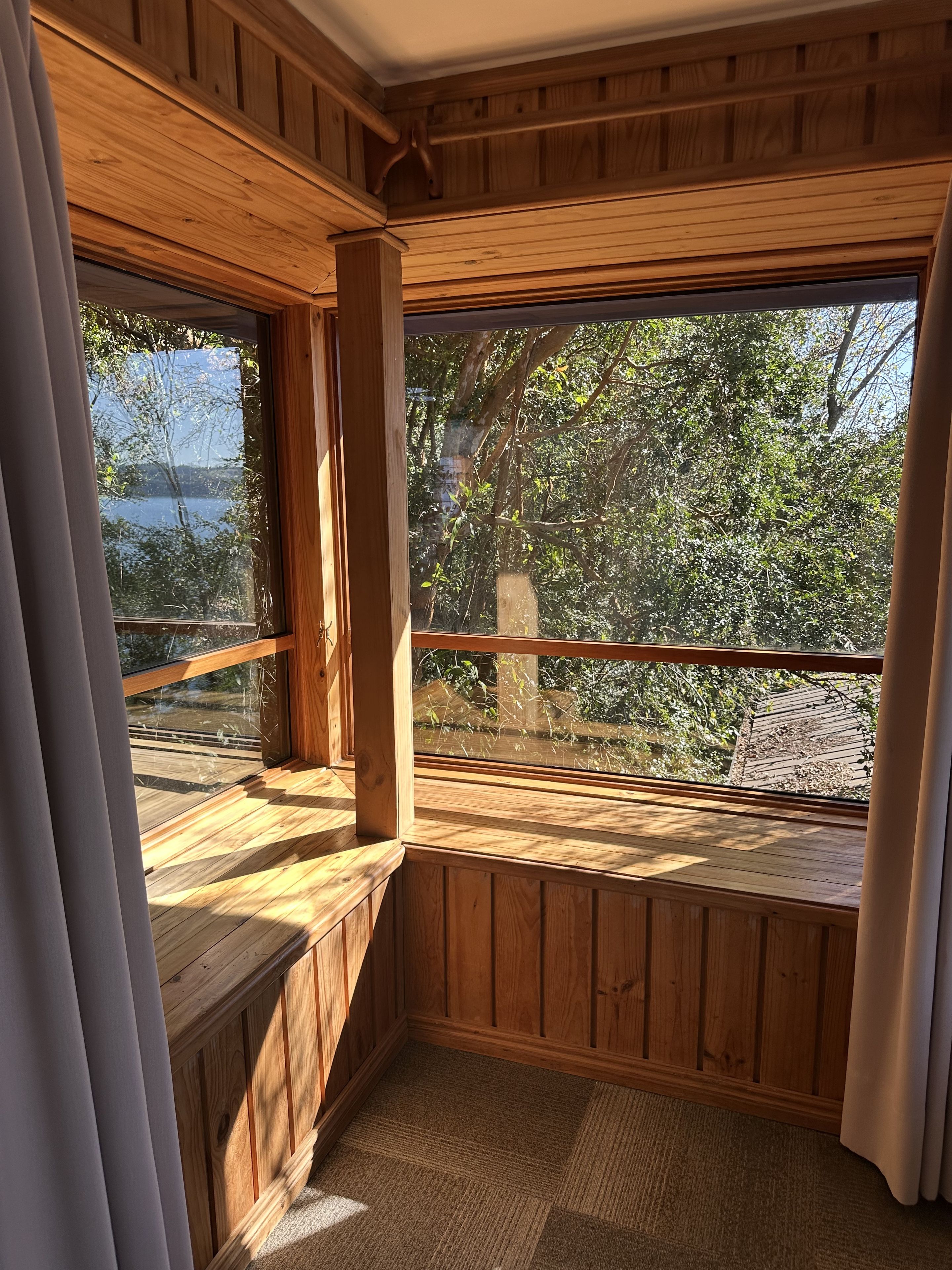 Une terrasse en bois offrant une vue sur un lac et des arbres.