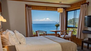 Una habitación de hotel con cama, escritorio con teléfono, mesa y sillas, y televisor.