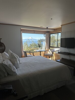 A hotel room with a bed, a TV, a table, and a chair.