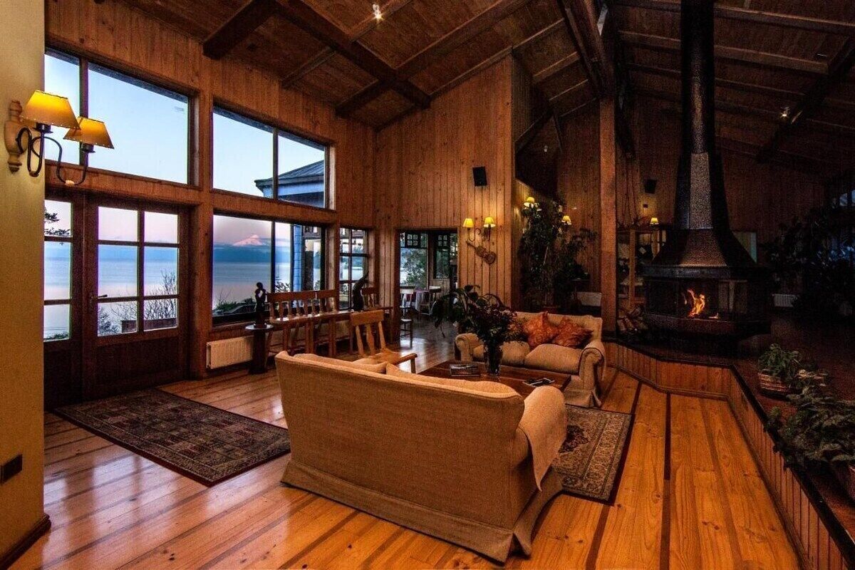 A spacious living room with a fireplace, large windows, and a view of the sea.