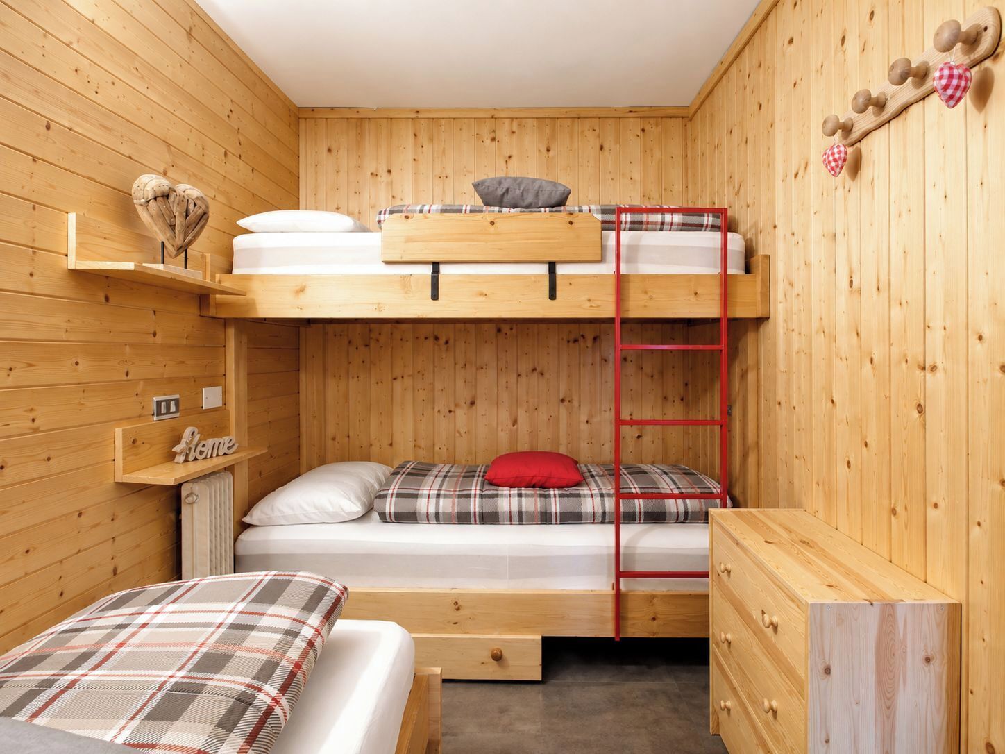A bunk bed room with a ladder, a small shelf, and a dresser.