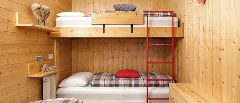 A bunk bed room with a ladder, a small shelf, and a dresser.