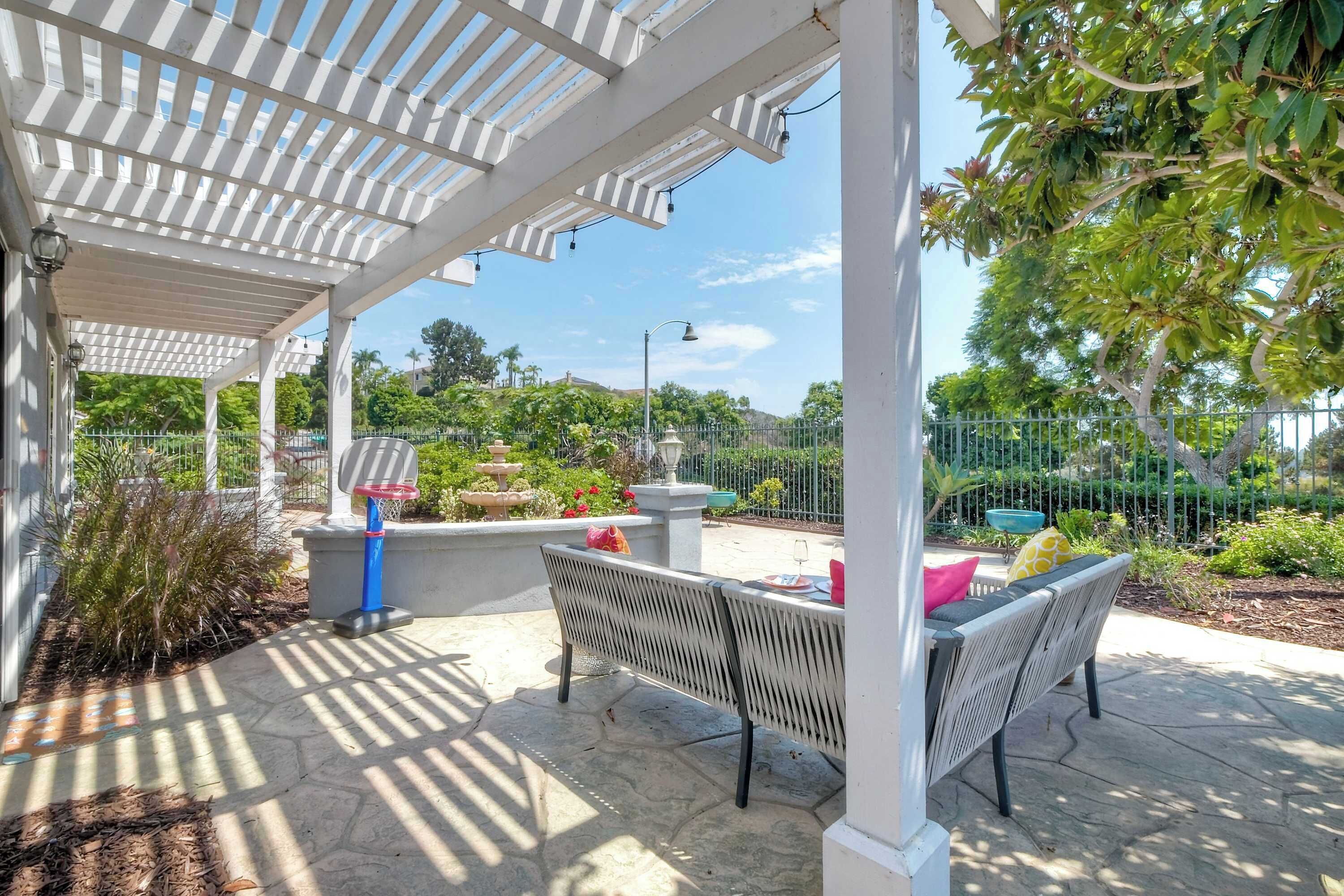 A covered outdoor area with a basketball hoop, seating, and a fountain.