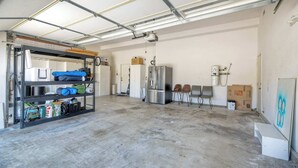 Ein geräumiger, im Industriedesign gestalteter Raum mit Metalldecke, einem Metallregal links sowie einem Edelstahlkühlschrank und einem Wasserspender rechts.