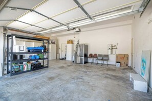 Um quarto amplo em estilo industrial, com teto metálico, uma estante de metal à esquerda e um refrigerador de aço inoxidável e um bebedouro à direita.