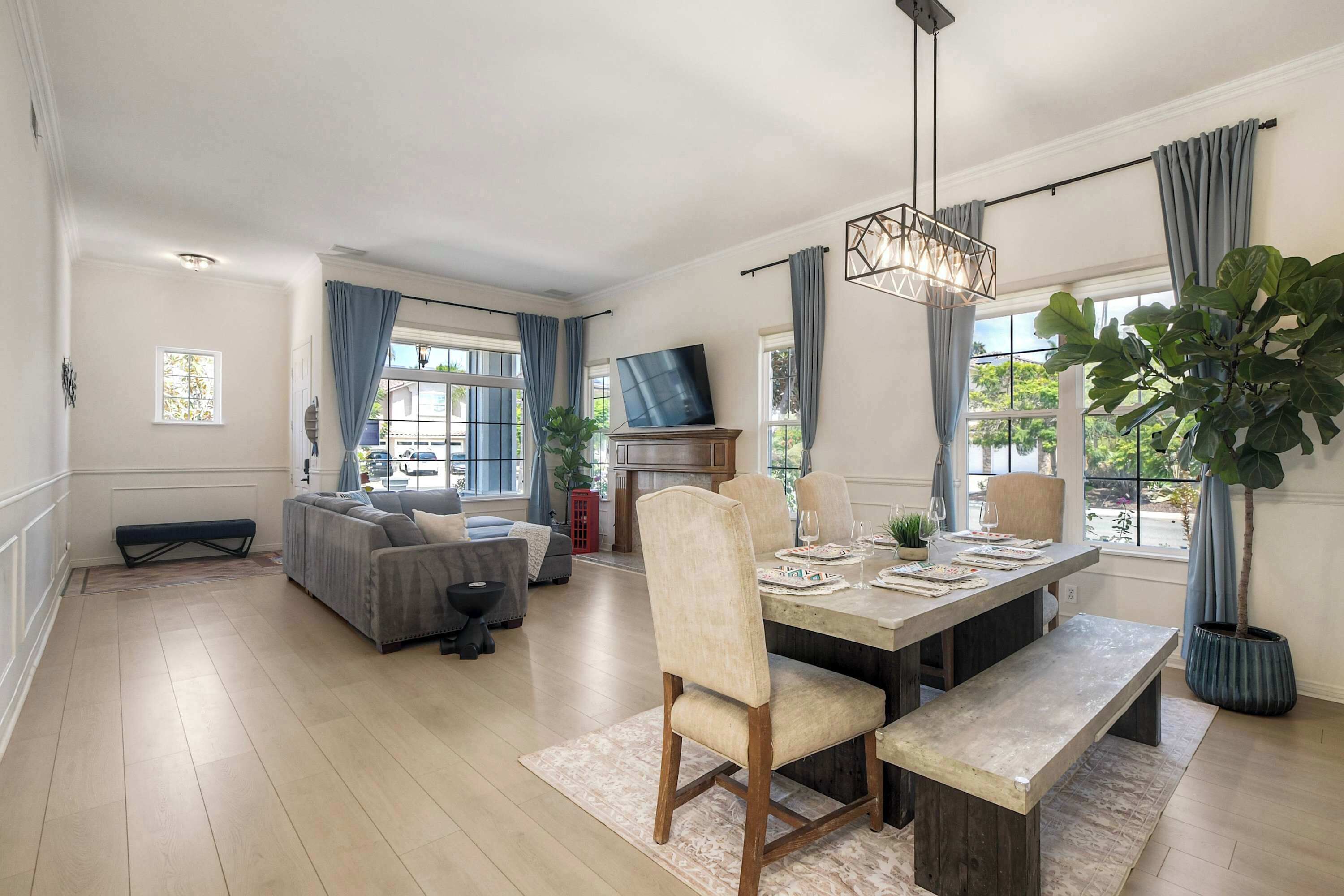 A spacious living area with a dining table, chairs, a sofa, and a television.