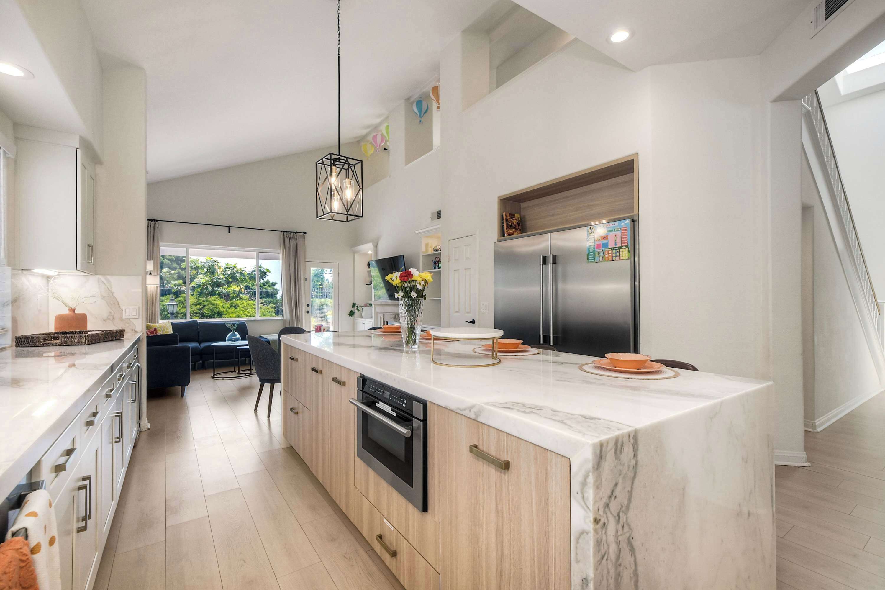 A modern kitchen with a large island, built-in appliances, and a dining area with a view.