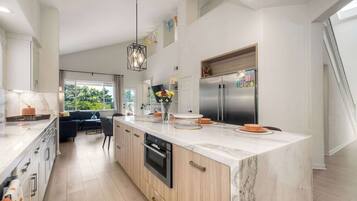 A modern kitchen with a large island, built-in appliances, and a dining area with a view.