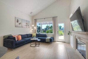 A modern living room with a sofa, a coffee table, and a fireplace. - Brick & Beach Family Retreat (Carlsbad)