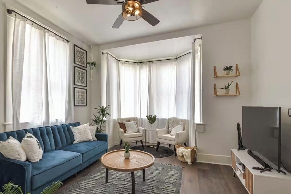 A living room with a blue sofa, two armchairs, a coffee table, and a TV on a stand.