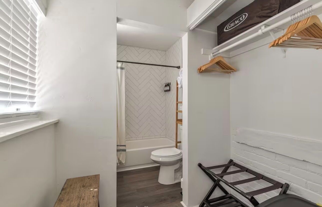 A bathroom with a white bathtub, a toilet, and a shower area.
