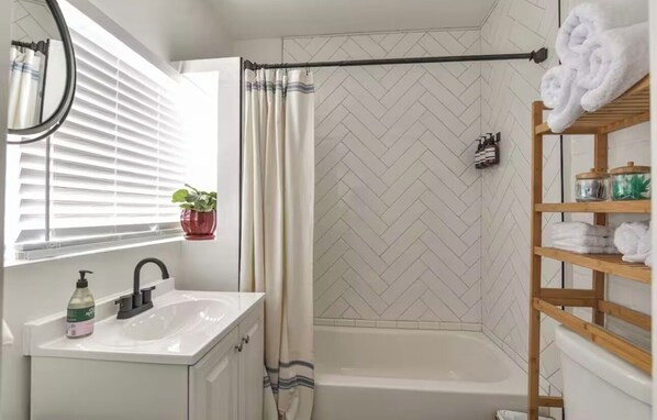 A bathroom with a shower, a sink with a mirror, and a towel rack. - Apartment in Historic Downtown Prescott - Fremont Room (Prescott)