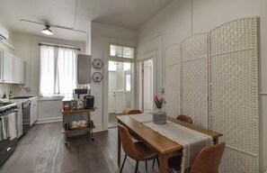 A compact kitchen with modern appliances, a dining area with a wooden table and chairs, and a decorative wall panel. - Apartment in Historic Downtown Prescott - Fremont Room (Prescott)