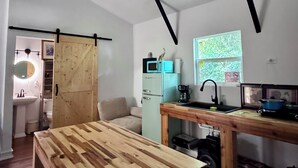 A modern kitchen with a wooden table, a refrigerator, and a window with a view.