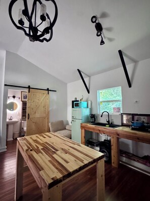 A modern kitchen with a wooden table, a refrigerator, and a window with a view.