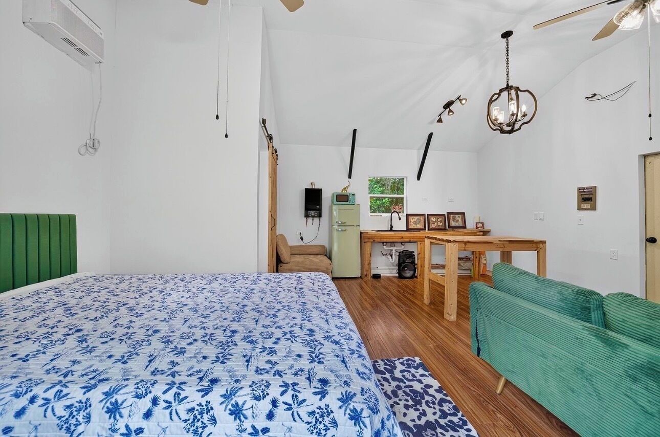 Un dormitorio con una cama, un escritorio, una silla y un sofá verde.