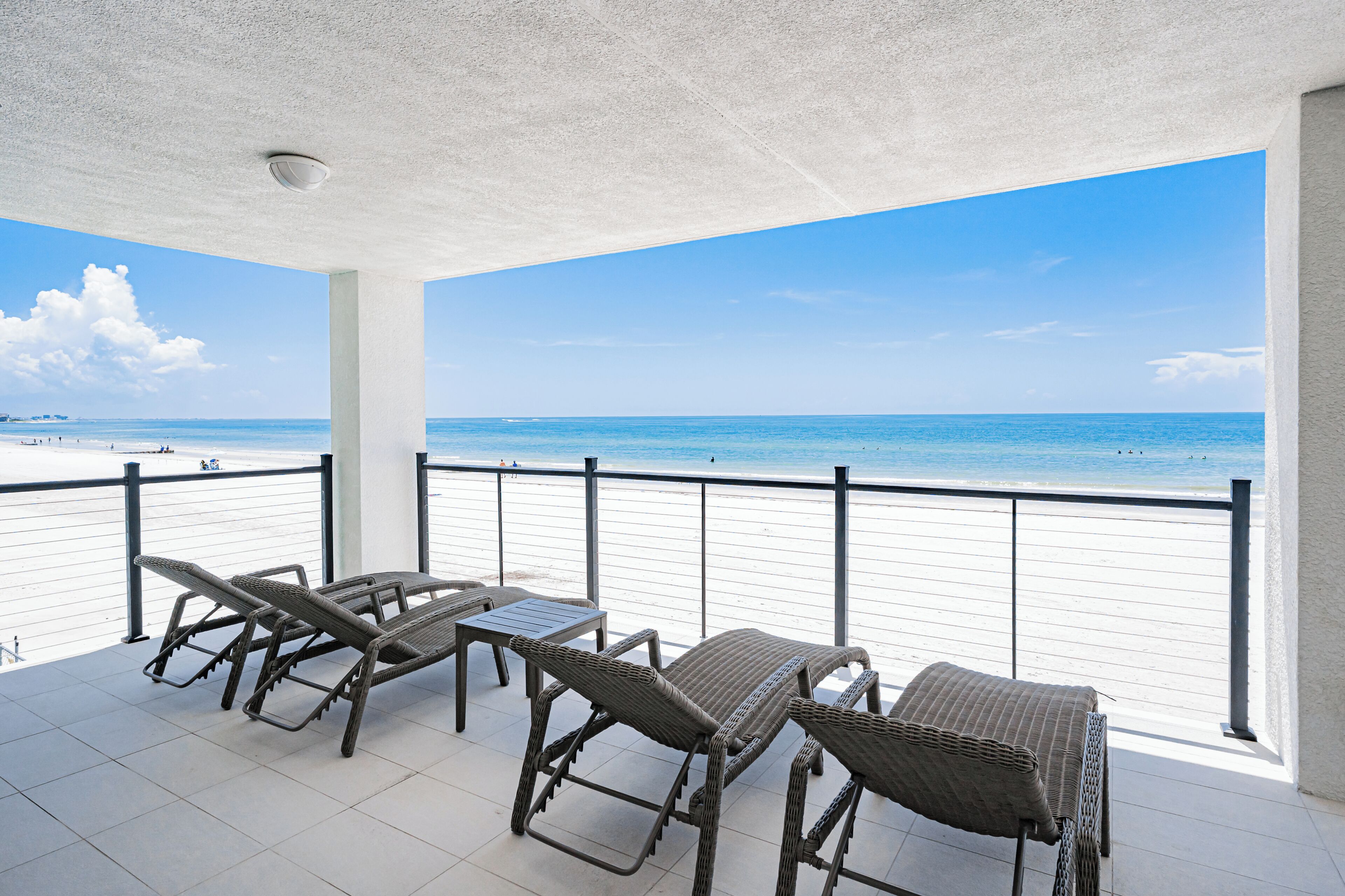 Un balcon abrité, doté de mobilier en osier, donnant sur une plage.