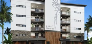 Ein mehrstöckiges Gebäude mit Balkonen, einem vertikalen, zentral platzierten Schild mit der Aufschrift 'Beach Flower' und einer Stein-Fassade.