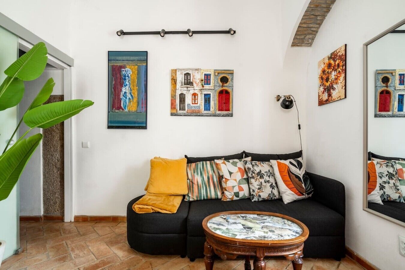 Un soggiorno con un divano nero, un tavolino rotondo e diverse opere d'arte alle pareti.