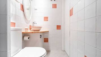 A bathroom with a toilet, sink, and shower area.