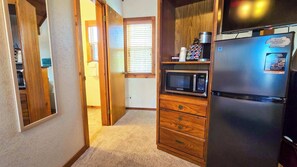 Una cocina compacta con refrigerador, microondas y cafetera sobre un mueble de madera.