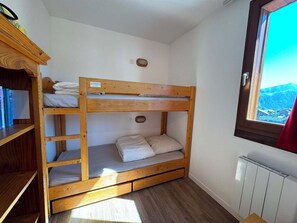 A bunk bed room with a view of mountains through a window.