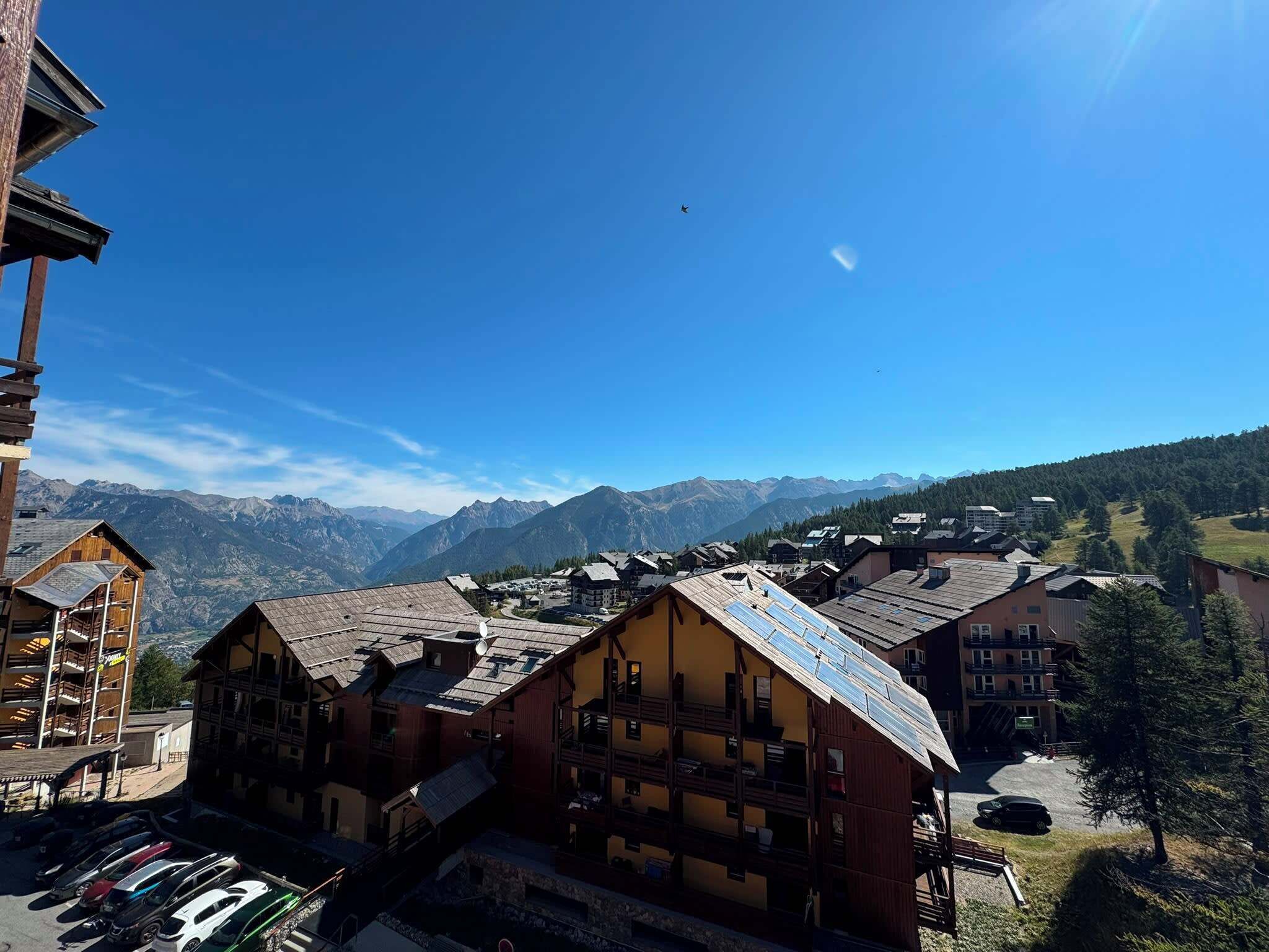 Un pueblo de montaña con edificios tradicionales de madera, cielo despejado y vistas a montañas distantes.
