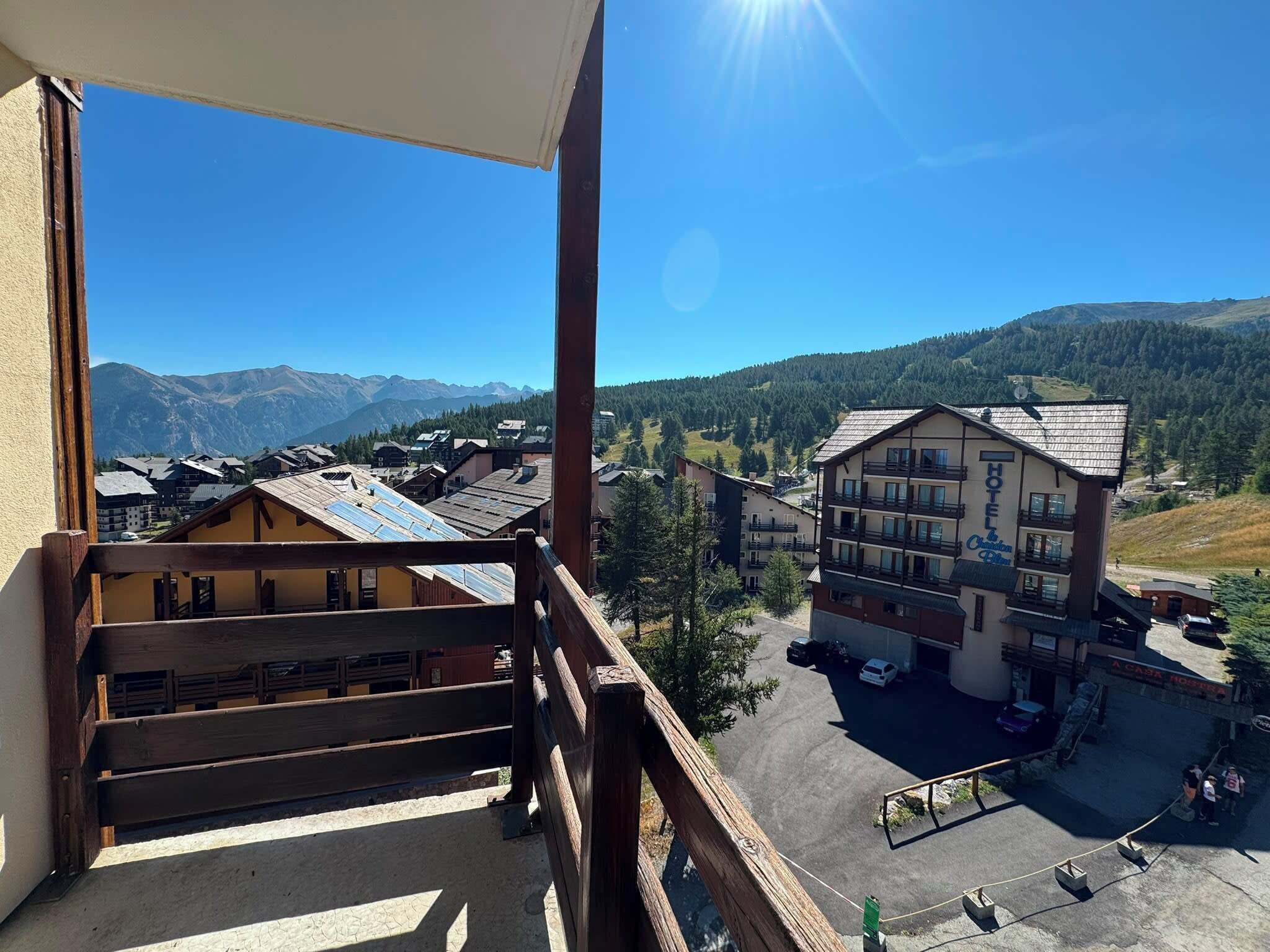 A hotel with a mountain view, a parking area, and a clear sky.