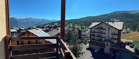 A hotel with a mountain view, a parking area, and a clear sky.