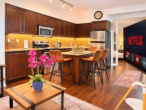 A modern kitchen with dark wood cabinets, stainless steel appliances, and a central island with bar stools.