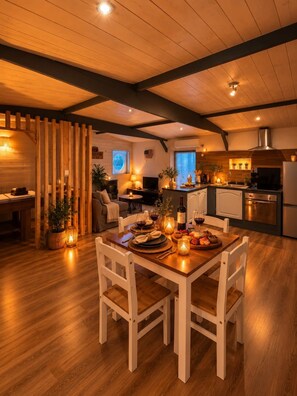 A cozy dining area with a wooden table set for two, surrounded by white chairs. - Love Room - Jacuzzi privatif - Romantique (Pissos)