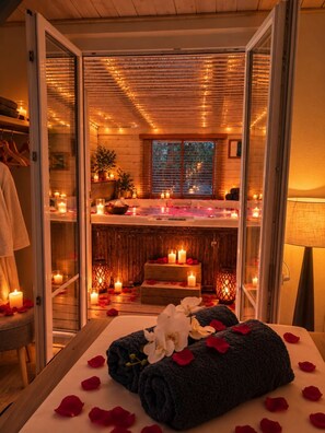 A spa room with a massage table, candles, and a hot tub. - Love Room - Jacuzzi privatif - Romantique (Pissos)