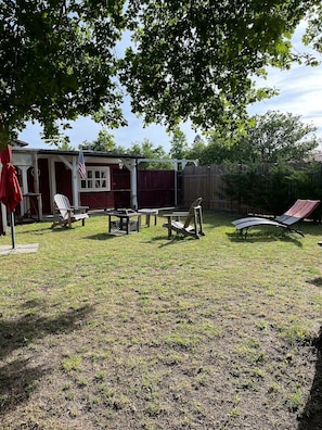 A backyard with a red building, outdoor seating, and a wooden fence.