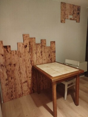 A wooden table with a white tabletop in a room with wooden paneling on the wall. - Magnifique studio au pied des montagnes (Prapoutel)