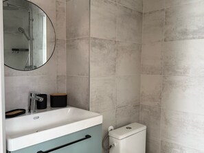 Ein Badezimmer mit Waschbecken, Spiegel, Toilette und Duschbereich.