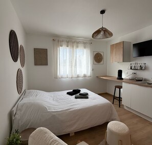 Ein modernes Schlafzimmer mit Bett, Schreibtisch, Stuhl, Fernseher und einem Fenster mit Vorhängen.