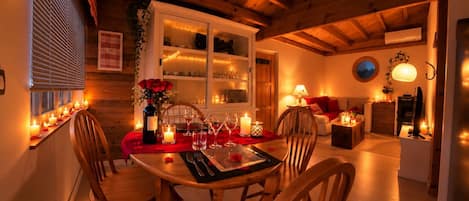 A cozy dining area with wooden furniture, candles, and a window with blinds.