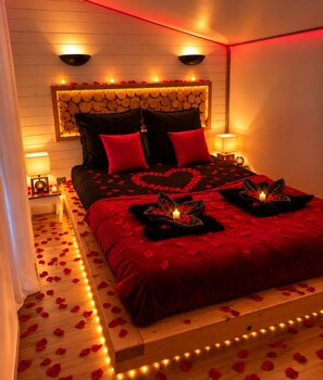 A bed with a red bedspread, black pillows, and a wooden headboard.