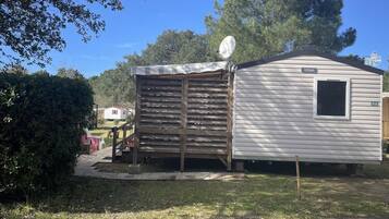 A mobile home with a satellite dish, a small porch, and a paved driveway.