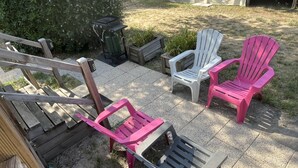 A patio area with outdoor furniture including a wooden deck, a trash bin, and several Adirondack chairs. - Mobil-home 3 chambres 1 sdb (Mimizan)