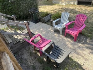 Eine Terrassenfläche mit Gartenmöbeln, darunter eine Holzterrasse, ein Mülleimer und mehrere Adirondack-Stühle.