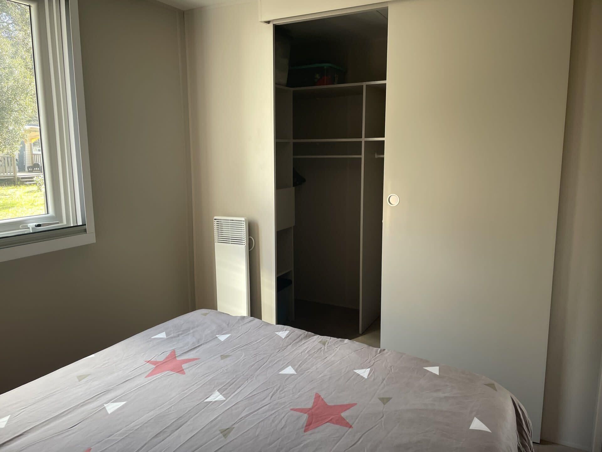 A bedroom with a bed, a window, and a closet.
