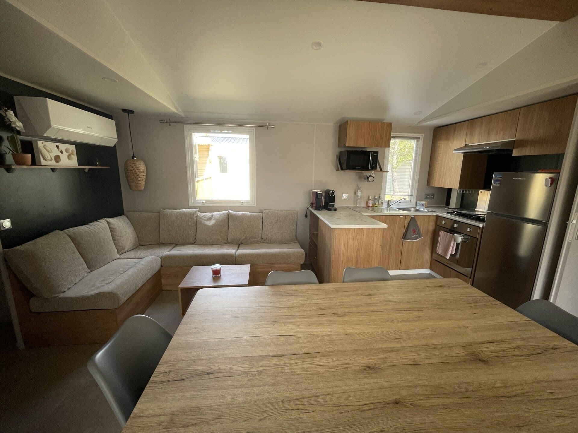 A compact kitchen with a wooden table, a built-in bench, and a microwave.
