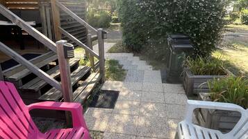 A covered outdoor area with a wooden staircase, a pathway, and outdoor seating.