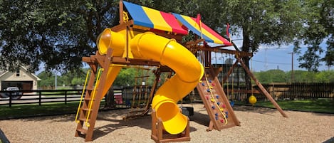 Un parque infantil con un tobogán amarillo y zona de escalada.