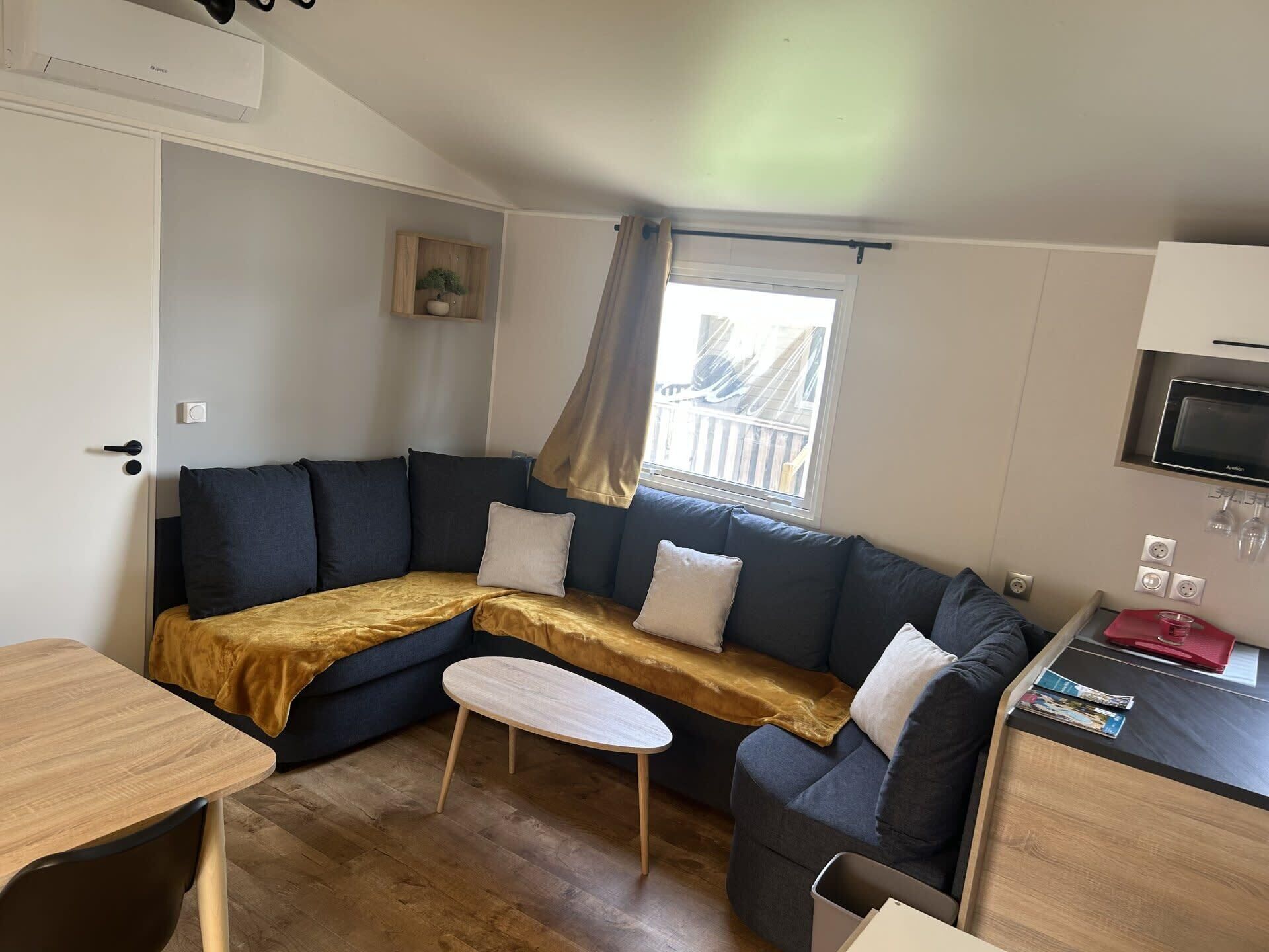 A compact living space with a sofa, a small table, and a kitchenette area.