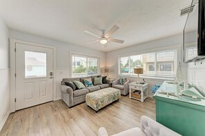 A room with a ceiling fan, a sofa, an ottoman, a side table, and a glass display case. - Seagrass Shores Unit 3 (Bradenton Beach)