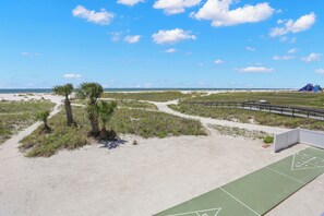 Una playa con un paseo marítimo, palmeras y una vista distante del océano.